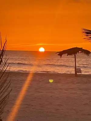 a sunset on the beach with an umbrella and a frisbee at Villa Nº25b Alfredo Marchetti suites on the beach Praia di Chaves in Cabeçadas