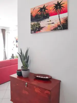 a living room with a red dresser with a painting on the wall at App Raffaele Estoril Beach Free Wifi & AC a step away from the sea in Sal Rei