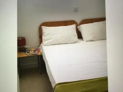a bed with white sheets and pillows next to a table at Leme Bedje GST84 3 bedroom apt with Panaramic views in Santa Maria