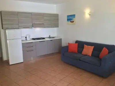 a living room with a blue couch and a kitchen at Apt14 Porto Antigo 1 with Pool and Beach views in Santa Maria