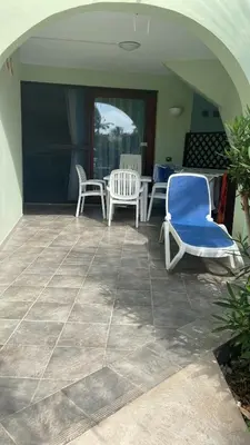 a patio with chairs and a table and a blue chair at Apt14 Porto Antigo 1 with Pool and Beach views in Santa Maria