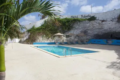 a swimming pool in front of a stone wall at Falucho Paradise Beach in Pedra Badejo