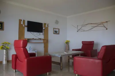 a living room with red chairs and a table and a tv at Falucho Paradise Beach in Pedra Badejo