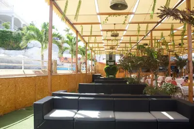 a restaurant with black tables and chairs and palm trees at Falucho Paradise Beach in Pedra Badejo