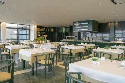 a dining room with white tables and chairs at Oasis Praiamar in Praia