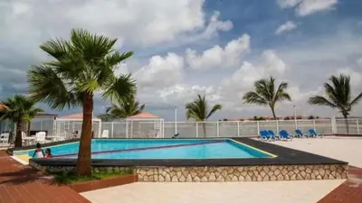 a large swimming pool with palm trees and a building at Beach Townhouse - Murdeira Village in Beirona