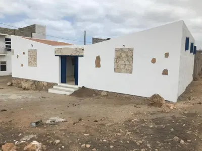a white building with a blue door and windows at Quintal do Maio in Vila do Maio
