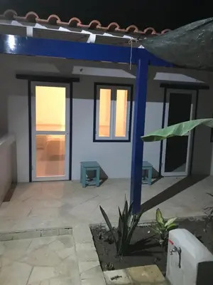 a small house with a blue wall and windows at Quintal do Maio in Vila do Maio