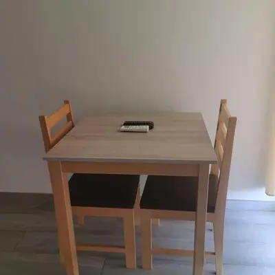 a wooden table with two chairs and a remote control on it at Ellen Apartamento T0 - Inforsal in Espargos