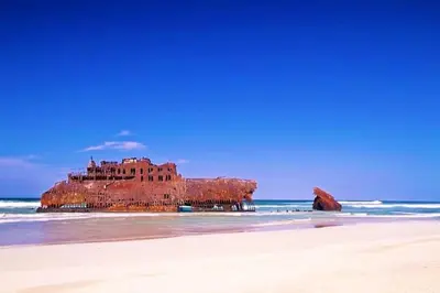 a building on the beach next to the ocean at Útulný apartmán na Praia de Chaves, Boa Vista in Sal Rei