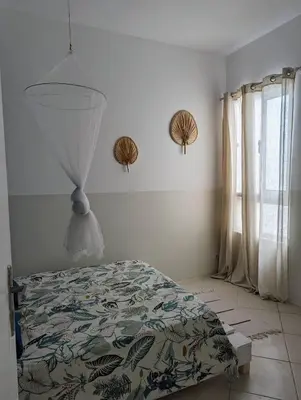 a bedroom with a bed with a comforter and a window at Tropical Leaves Sea view penthouse ca Greta 2 floor in Sal Rei