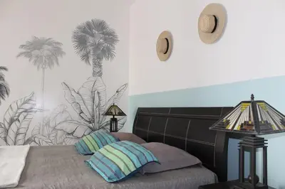a bedroom with a bed with palm trees on the wall at Tropical Leaves Sea view penthouse ca Greta 2 floor in Sal Rei