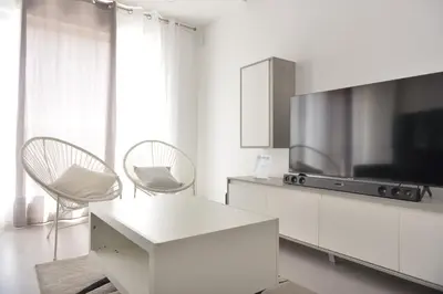 a white living room with a tv and a table and chairs at Duarte Apartments - Lux in Mindelo