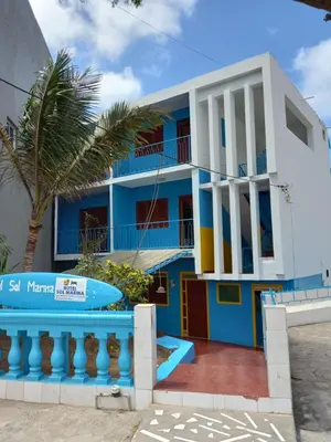 a blue and white house with a palm tree at Hotel Sol Marina in Tarrafal