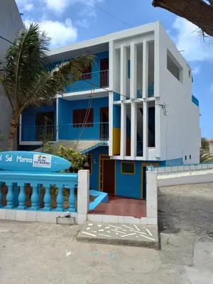 a blue and white building with a palm tree at Hotel Sol Marina in Tarrafal