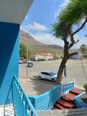 a white car parked in a parking lot with a tree at Hotel Sol Marina in Tarrafal