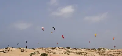 a bunch of kites flying in the sky over the sand at Atlantic Sal Hostel in Santa Maria
