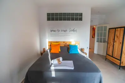 a bedroom with a large bed with colorful pillows at Apartamento Fátima Amwilla Guesthouse in Mindelo