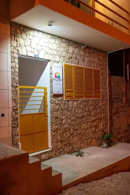 a building with a yellow door and a stone wall at Amwilla Guesthouse Quarto WC privativo Elsa in Mindelo