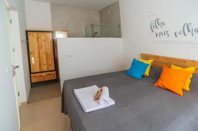 a bedroom with a bed with colorful pillows at Amwilla Guesthouse Quarto WC privativo Elsa in Mindelo