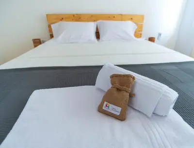 a teddy bear sitting on top of a bed at Amwilla Guesthouse Quarto WC privativo Elsa in Mindelo