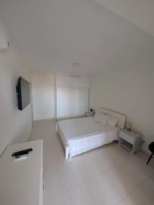 a white bedroom with a bed and a tv at Casa Relaxod in Santa Maria