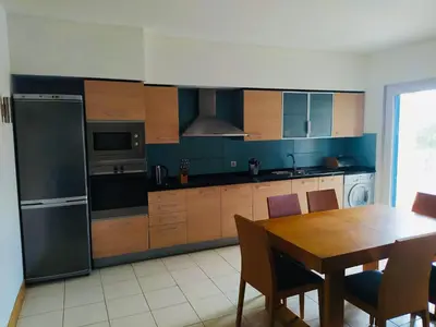 a kitchen with wooden cabinets and a table with chairs at Apartamento Privado Vila Verde in Santa Maria