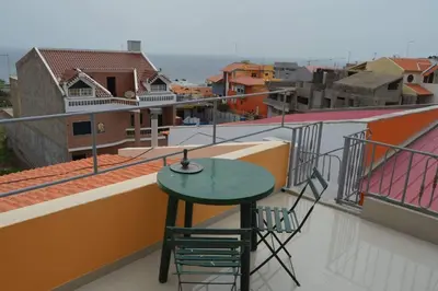 a table and chairs on the balcony of a building at Apartamento T1 Mobilado com Wi-Fi in Praia