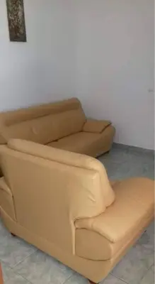 a brown couch and a chair in a room at Apartamento T1 Mobilado com Wi-Fi in Praia