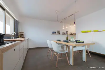 a kitchen with a wooden table and white chairs at Seafront Holiday House on the Mindelo Bay in Mindelo