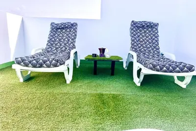 two chairs and a table in a room with green carpet at ANIMOSS! APARTMENTS - 10 modern apartments near city center & beach in Santa Maria