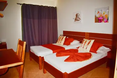two beds in a hotel room with red sheets at Damfjord Boutique Hotel in Santa Maria