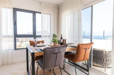 a dining room with a table and chairs and windows at Penthouse with jacuzzi and sea view, Morabeza Deluxe in Mindelo
