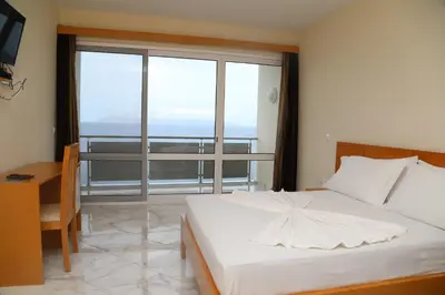 a bedroom with a bed and a desk and a large window at Cruzeiro Guest House in São Filipe