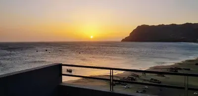 a sunset over a beach with the sun setting over the ocean at Casa JPi in São Pedro