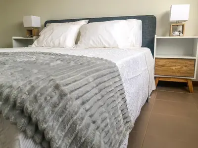 a bed with a white comforter and two night stands at Brand New Chic Appt in Mindelo at Great Rates in Mindelo