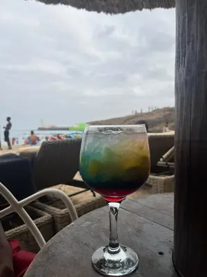 a glass of wine sitting on a table near the beach at Apartamento Os Bidons in Praia