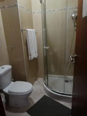 a bathroom with a toilet and a glass shower at Yria Residencial in Porto Novo