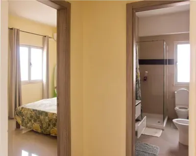 a bathroom with a bed and a toilet and a mirror at Praia Capital Residence Aparthotel in Praia