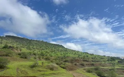 a green hill with a blue sky and clouds at Praia Capital Residence Aparthotel in Praia
