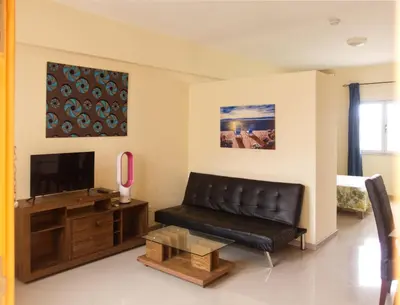 a living room with a black leather couch and a tv at Praia Capital Residence Aparthotel in Praia