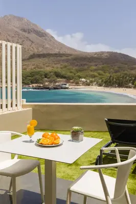 a table and chairs with a plate of oranges and a beach at Oasis Tarrafal Alfandega Suites in Tarrafal