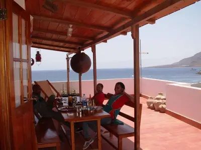 a group of people sitting at a table with a view of the ocean at Edificio Magico in Tarrafal