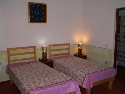 two beds in a room with pink sheets at Edificio Magico in Tarrafal