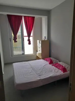 a bedroom with a bed with pink pillows and a window at Apartamento T2 em Sal Rei - Boavista in Sal Rei