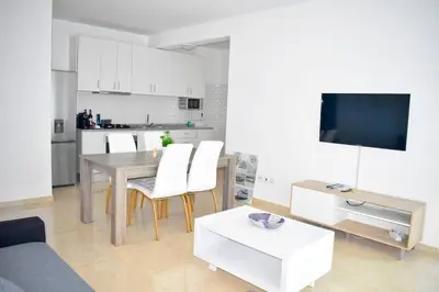 a living room with a table and a kitchen at Lovely - Luxury 2 Bedrooms 500m from the Beach in Santa Maria
