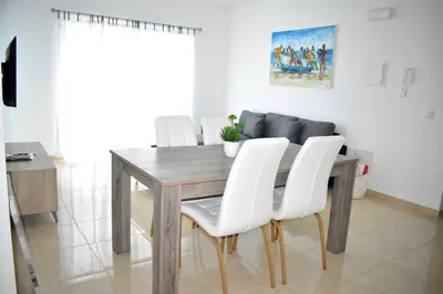 a dining room table with white chairs around it at Lovely - Luxury 2 Bedrooms 500m from the Beach in Santa Maria