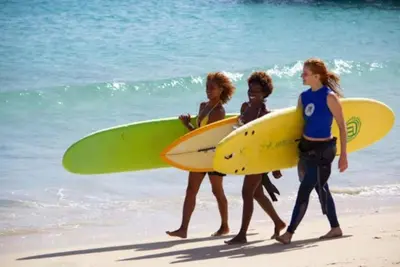 three people walking on the beach with their surfboards at Time Out Pátio Antigo AC Wifi in Santa Maria