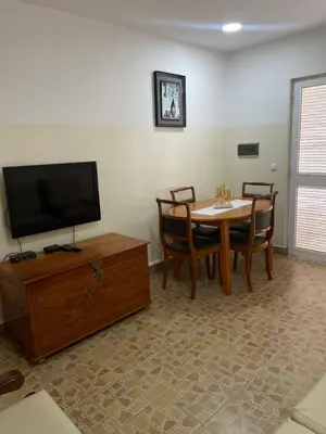 a living room with a table and a flat screen tv at Apartamentos Avenida in Praia