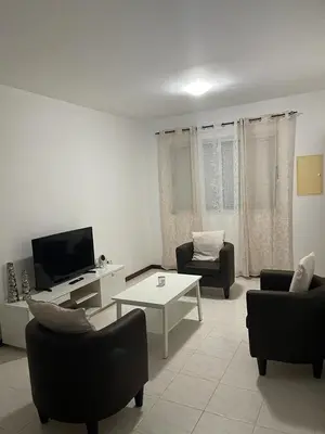 a living room with couches and a tv and a table at Apartamento Vila Santa Bárbara ,Bloco F RChão Dirt,Santo Antão,Cabo Verde in Mão para Trás
